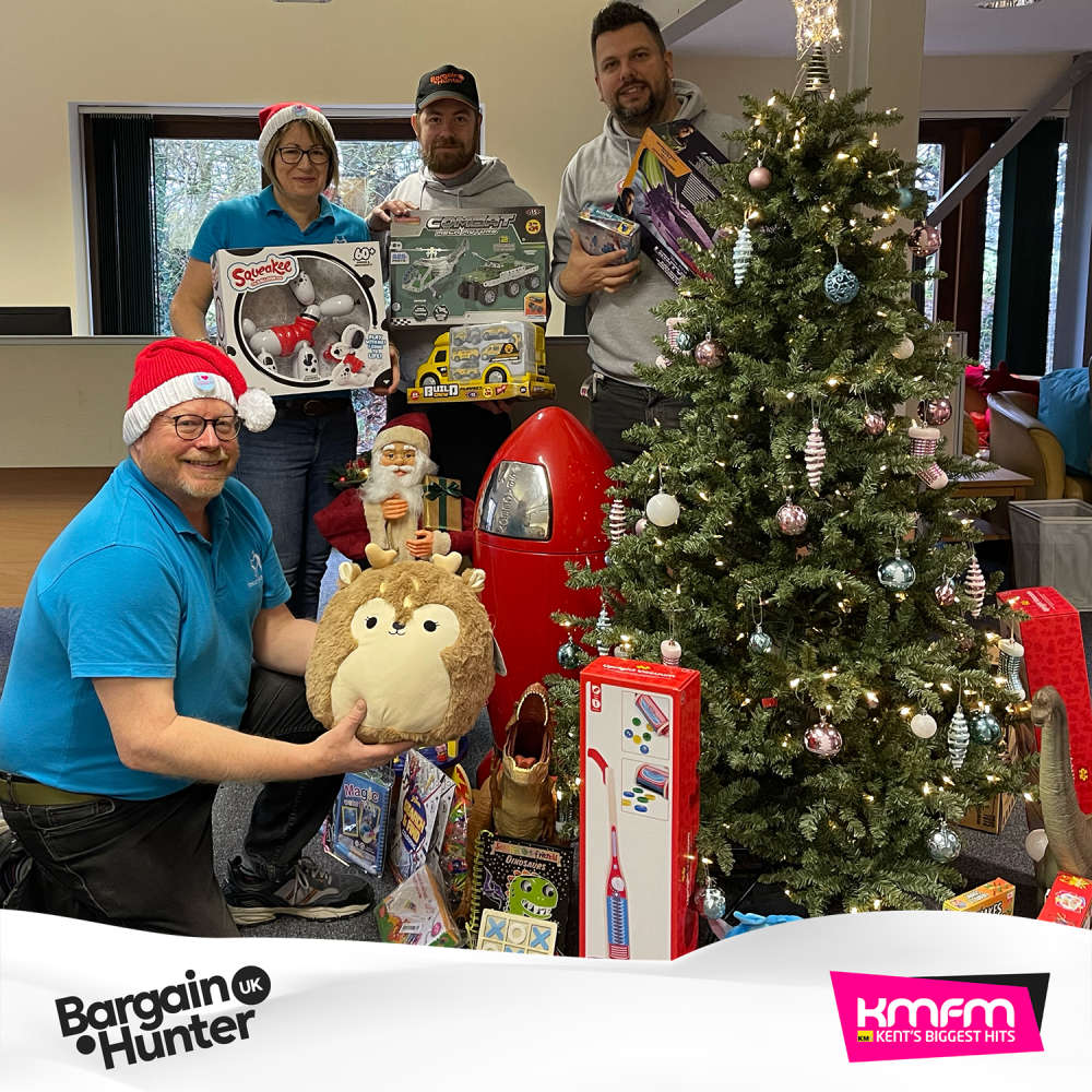 kmfm and Bargain Hunter drop by the office. Neil and Debbie pose with the gifts under the office Christmas Tree.