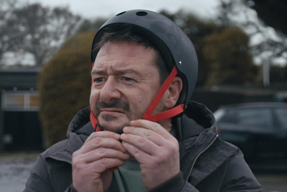 'The Beginner' - man puts on his helmet to practice skateboarding...